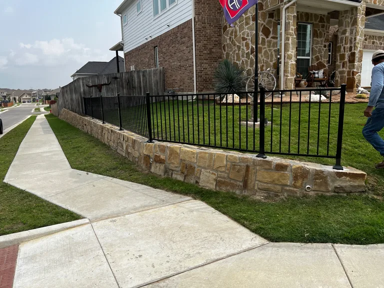 Metal fence on retaining wall